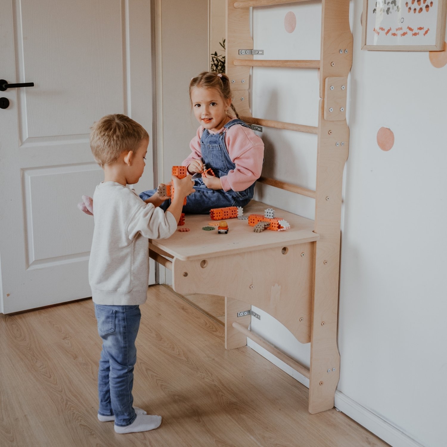 Dzieci bawią się zabawkami na biurku przymocowanym do drabinki gimnastycznej